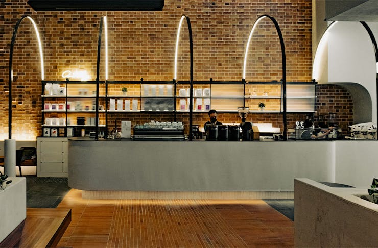 a concrete coffee bar under curved steel rods in a brick cafe