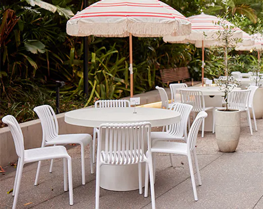 tables and chairs under striped umbrellas in a laneway