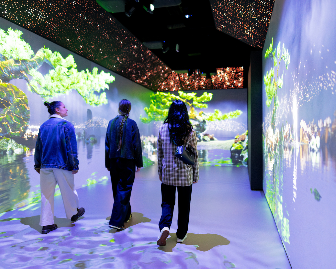 Three people walking through installation