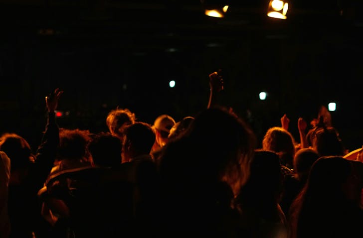 A crowd of people at a concert with their hands in the air.