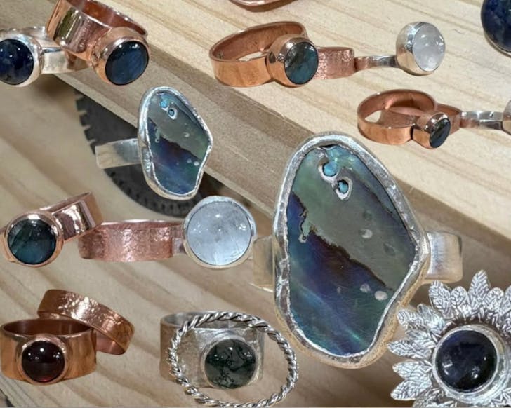 An assortment of superimposed beginner-made jewellery on a light wood background.
