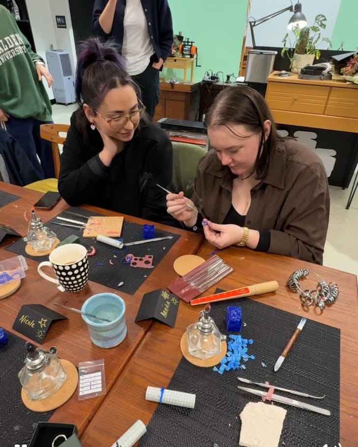 A group of girls gather around a table making jewellery