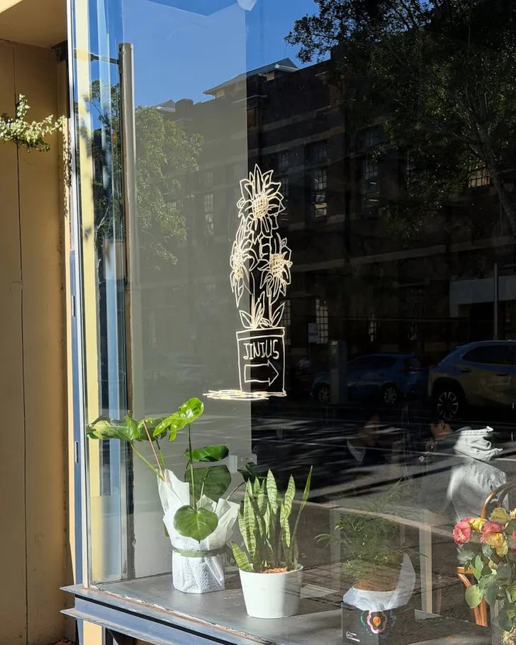 The logo for Dawes Point cafe Jinius on the glass front window.