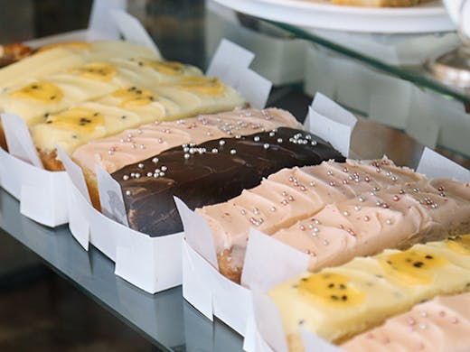 a row of bar cakes with different icings in a cabinet