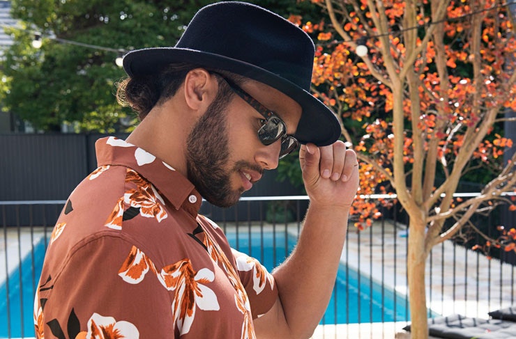 A model wearing a floral shirt and a fedora. 