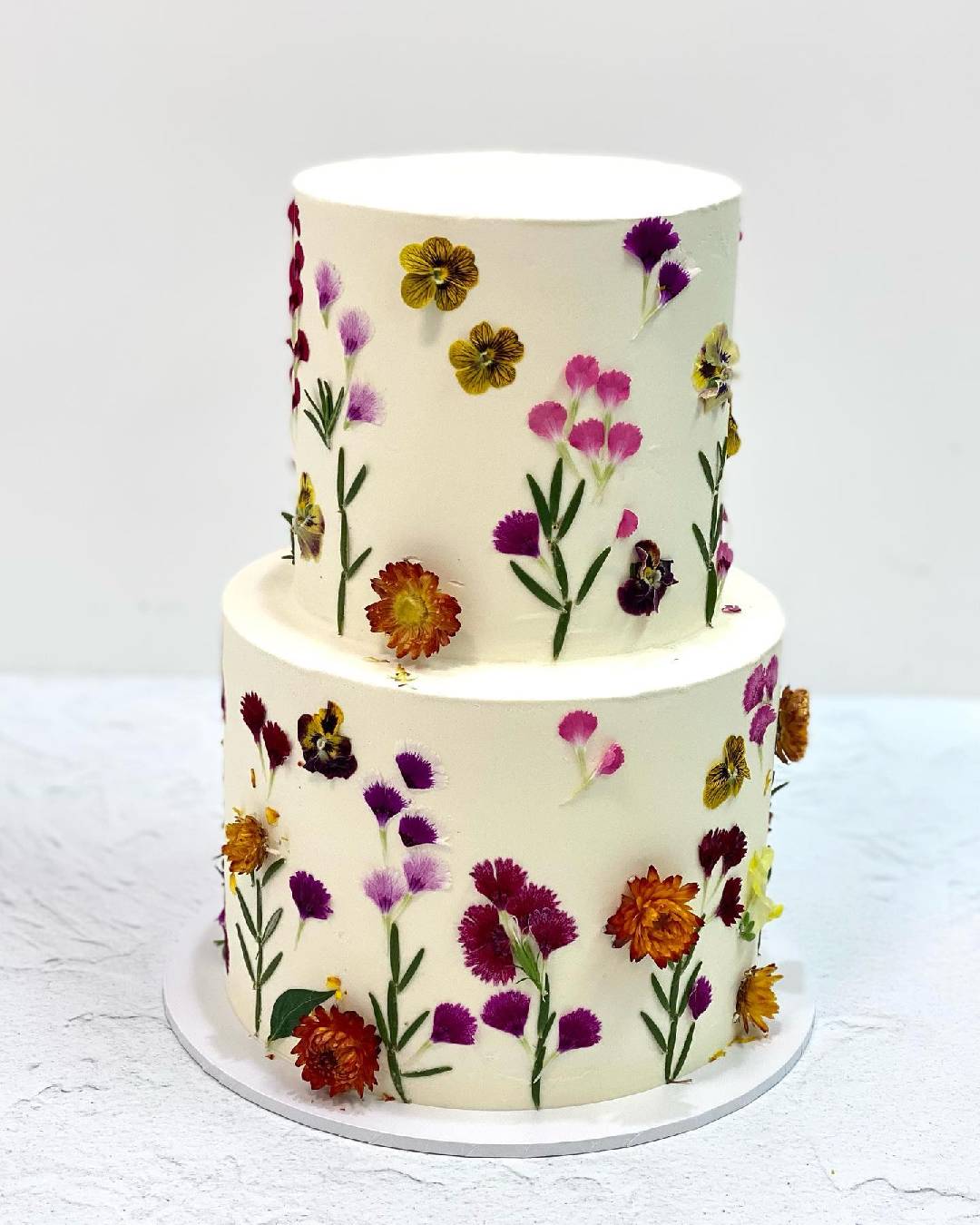 white cake with colourful flowers stuck to the icing 