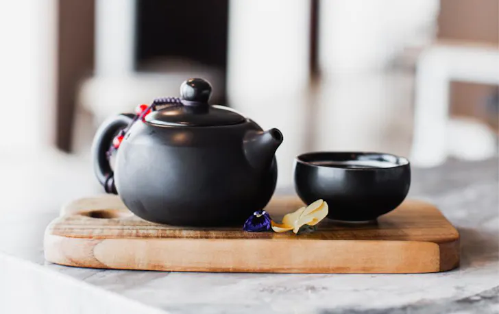 a small black teapot and cup