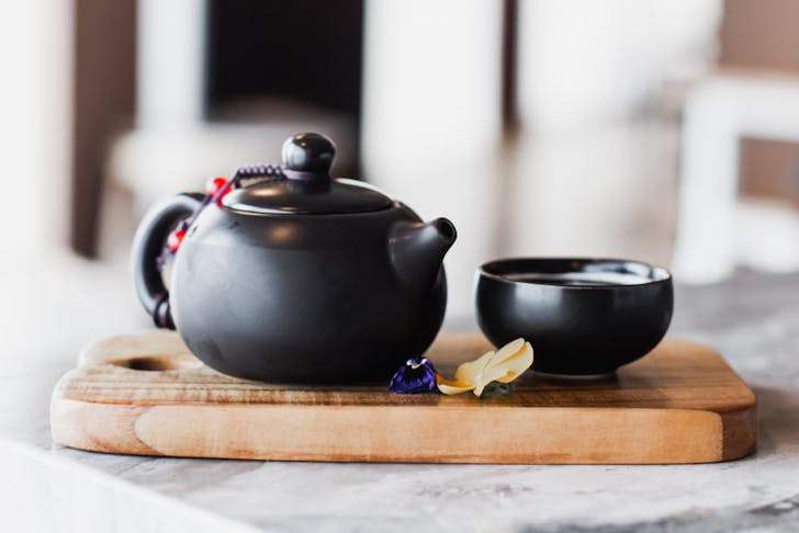 a small black teapot and cup