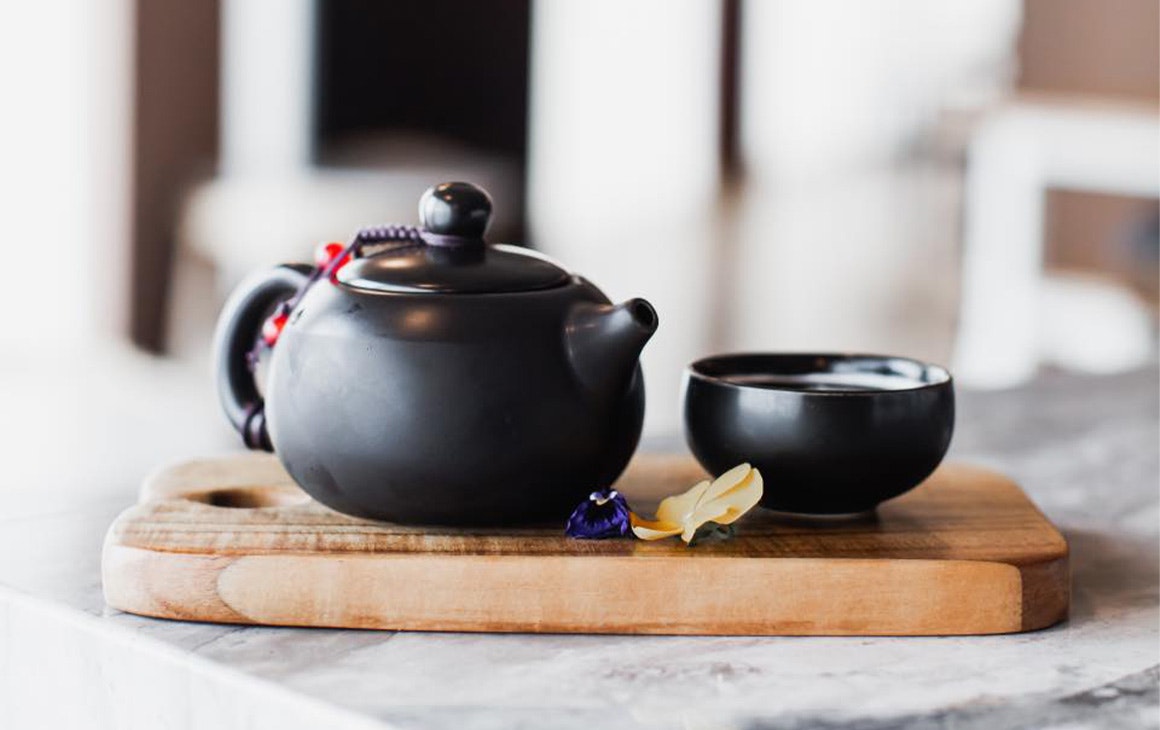 a small black teapot and cup