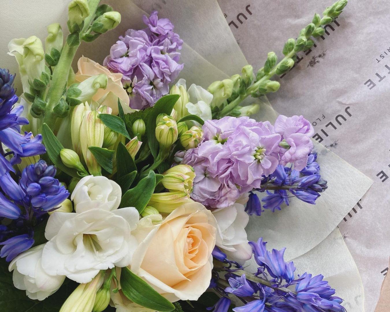 A pretty bouquet of white and purple blooms wrapped in the signature Juliette Florist paper