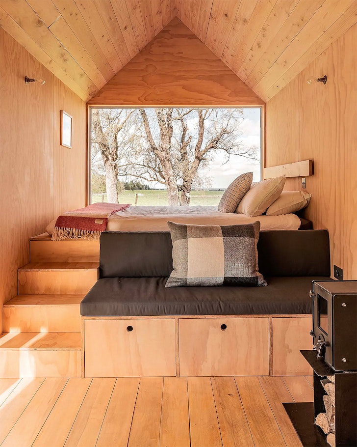 A view of the bed next to a big window at Kererū Retreat one of the best NZ Airbnbs