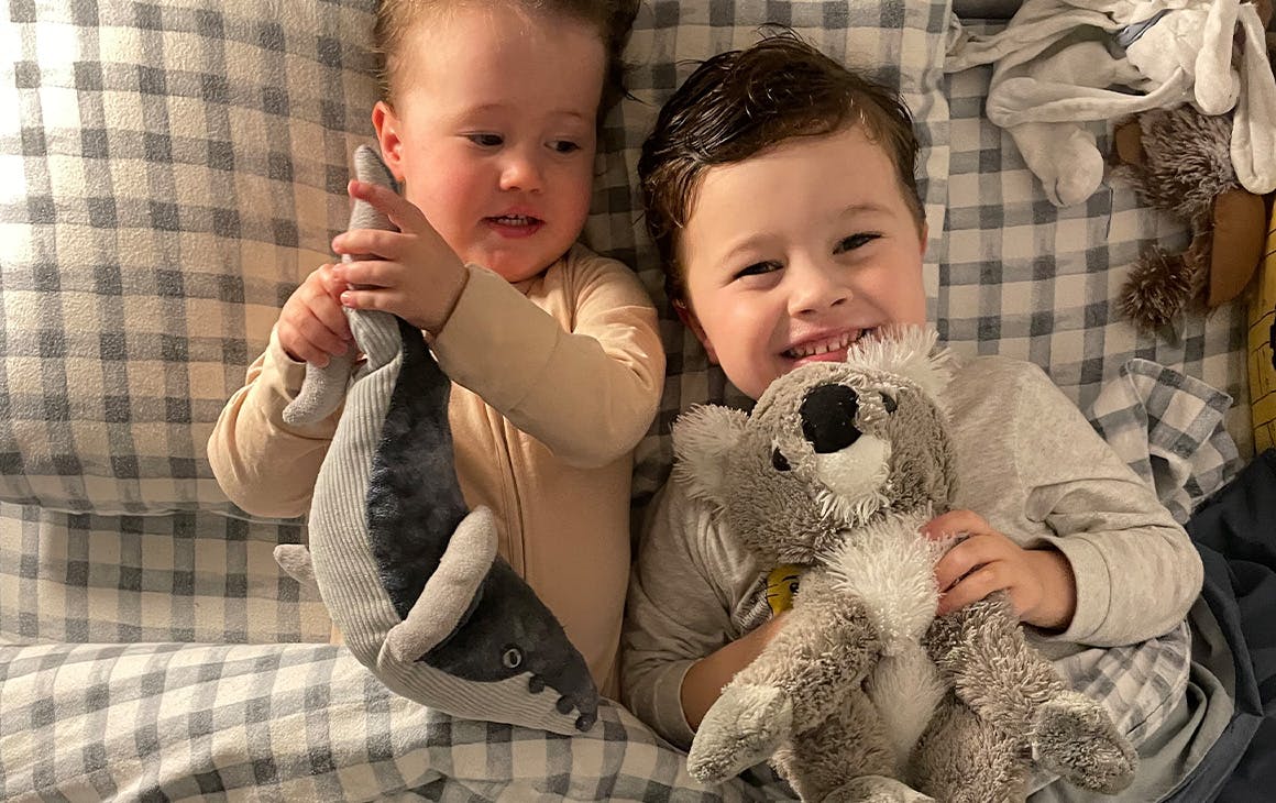 two children in bed with soft toys