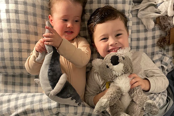 two children in bed with soft toys
