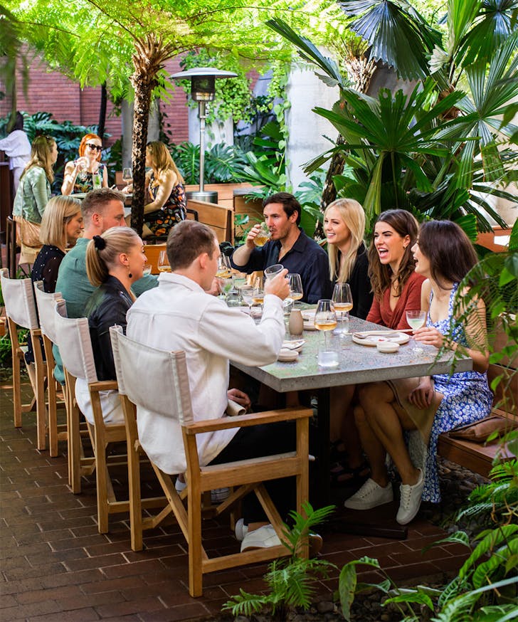 people sitting at a table in a leafy outdoor setting