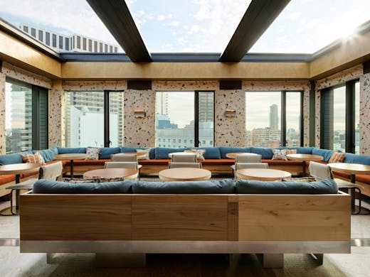A glass roof and large glass windows surround the lounge bar at Kiln at Ace Hotel