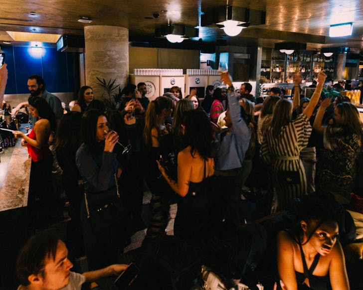 A wide shot of an indoor venue at Ace Hotel Sydney full of a crowd of people dancing and enjoying themselves.