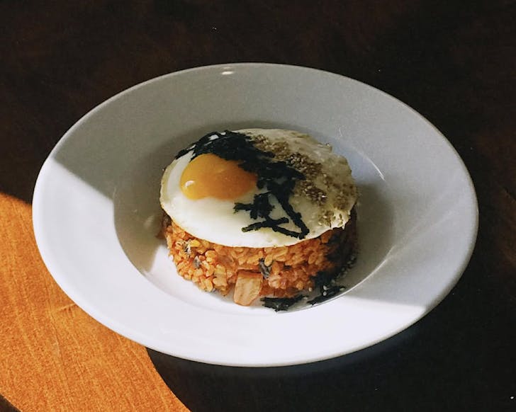 A bowl of kimchi fried rice topped with a fried egg.