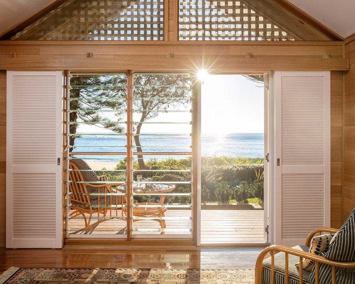 A view of the water through the doors of a room at Kims Beachside Retreat some of the best Central Coast accommodation