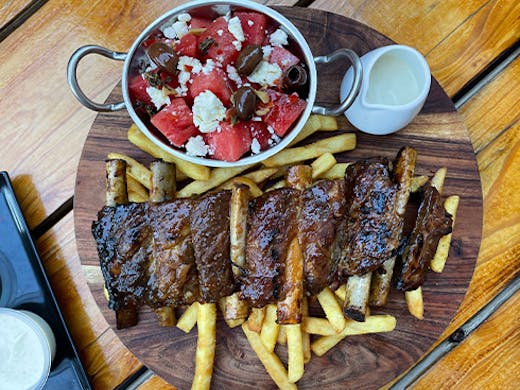 a platter of ribs and chips with a side of watermelon salad