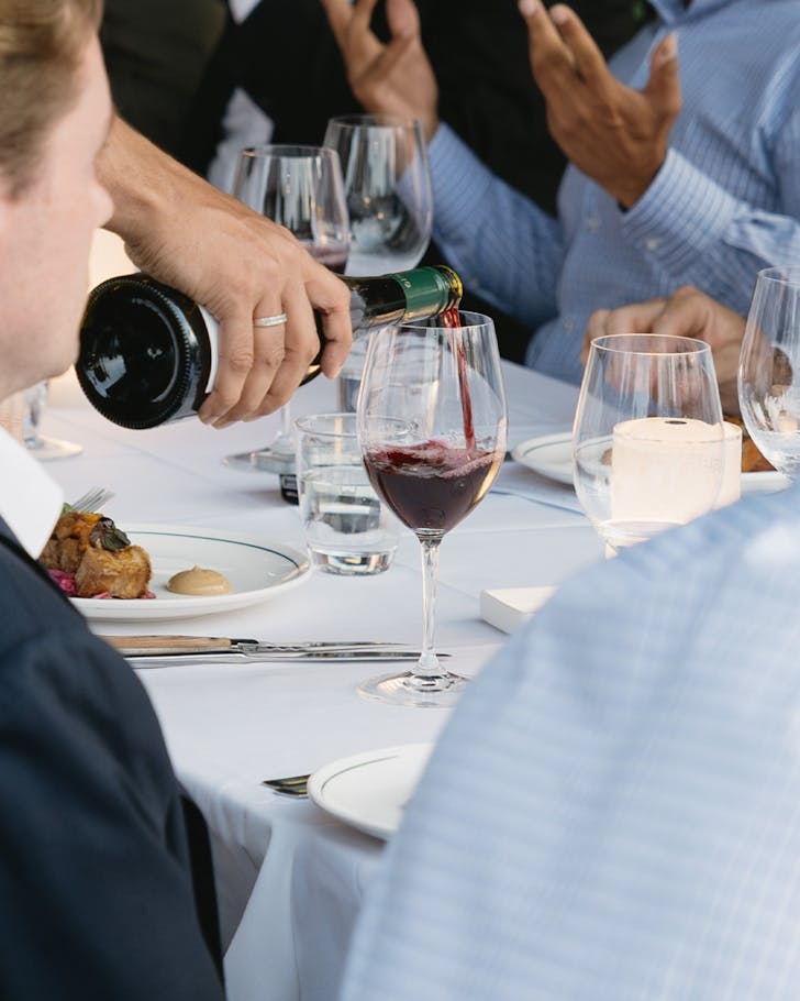 hand pours a glass of red wine for the table at kingsleys