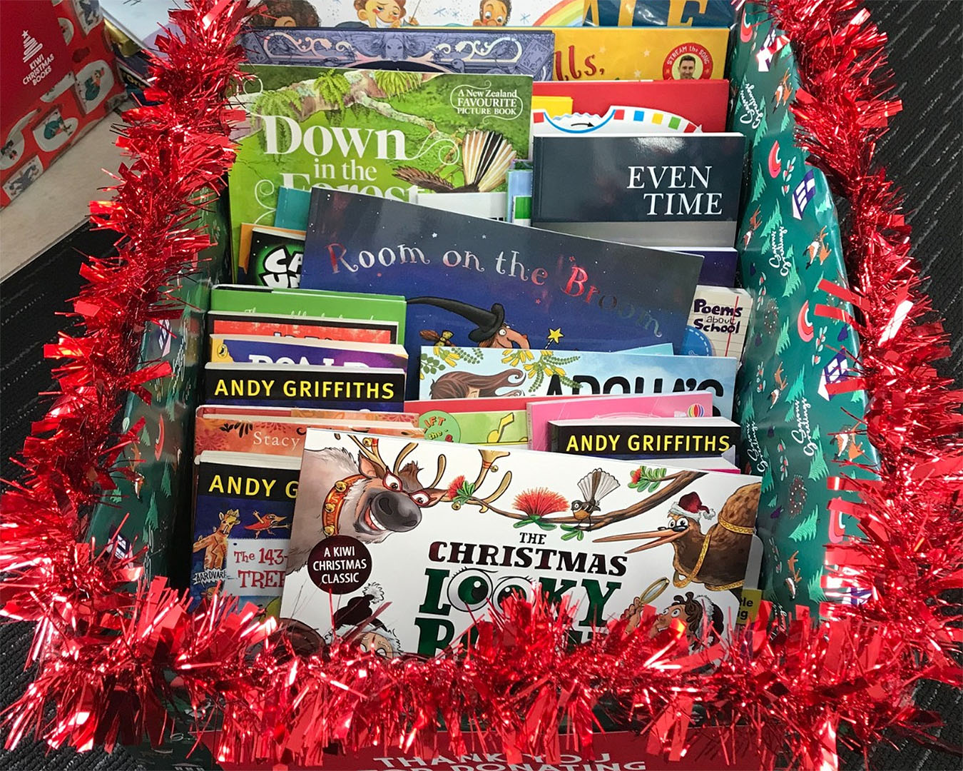 A box full of children's books surrounded by tinsel. 