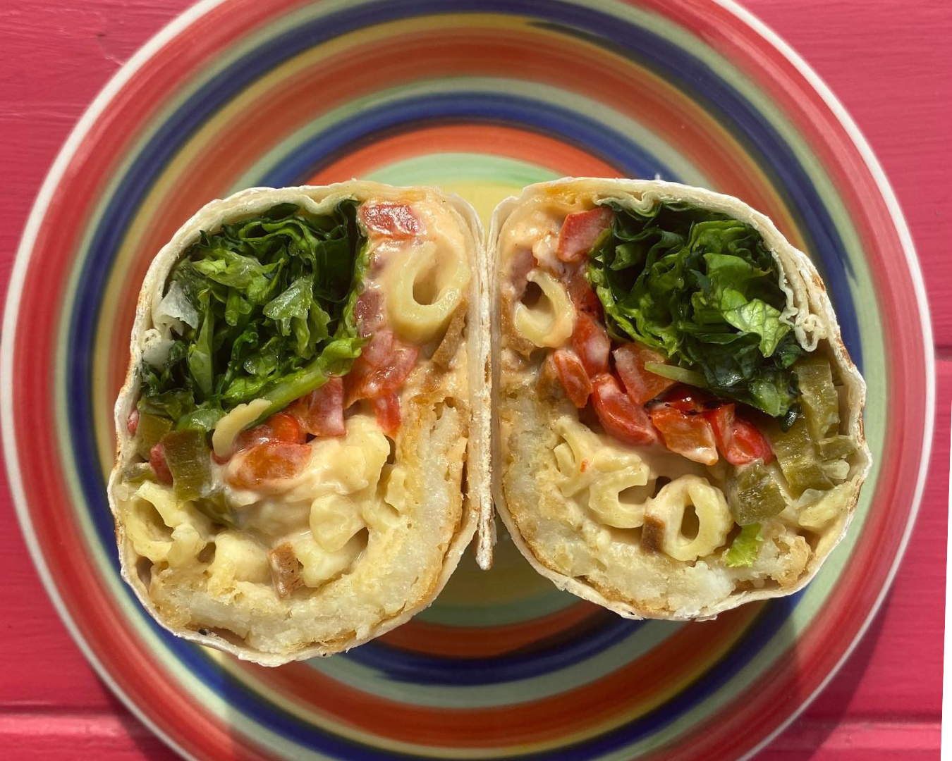 mac ‘n’ cheese burrito sitting on a bright rainbow plate