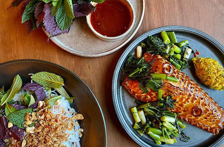 A fillet of kingfish encrusted in pastry, sat on a plate next to other Vietnamese ingredients.