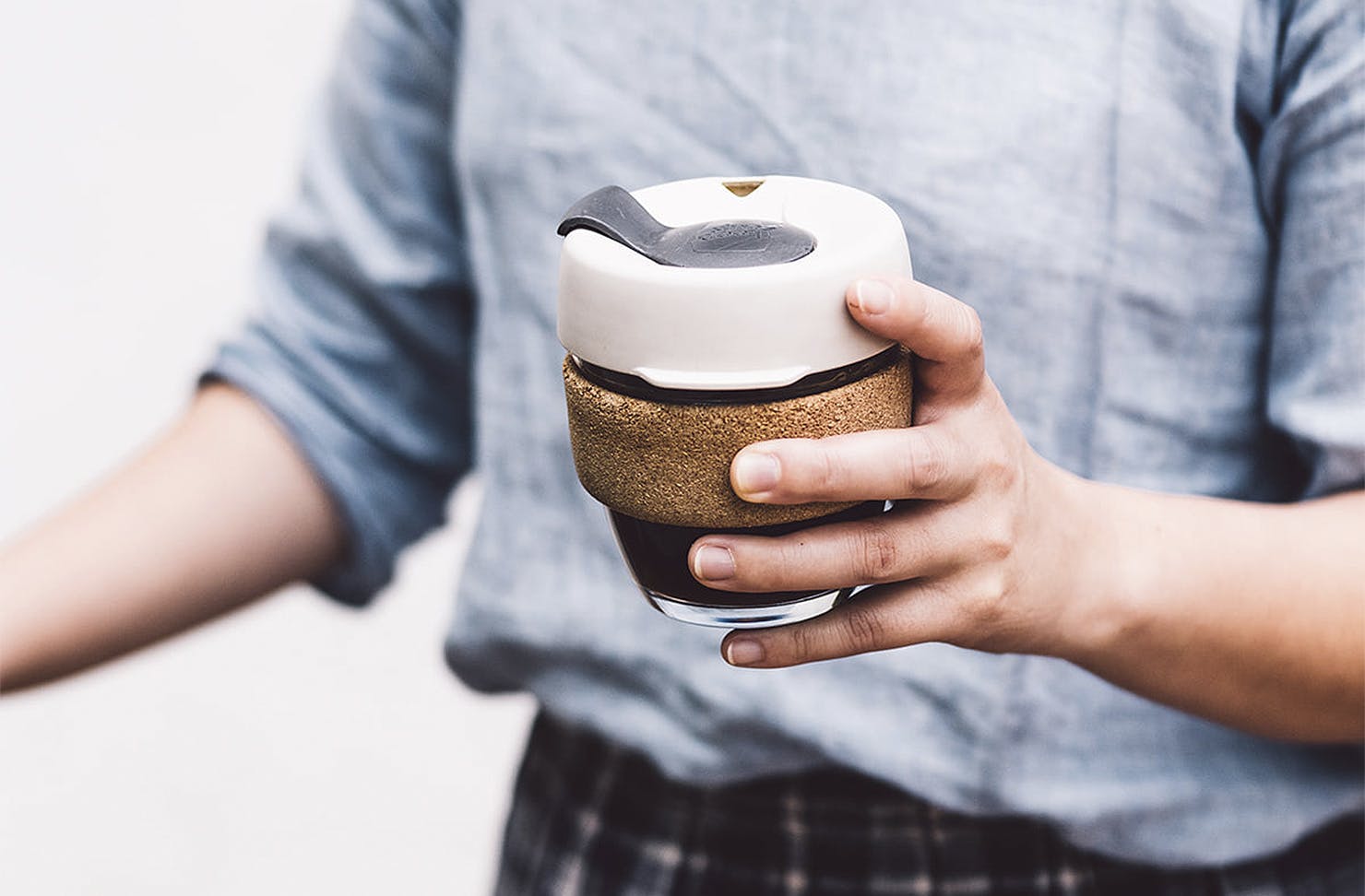 A person holds a keep cup in their hands.