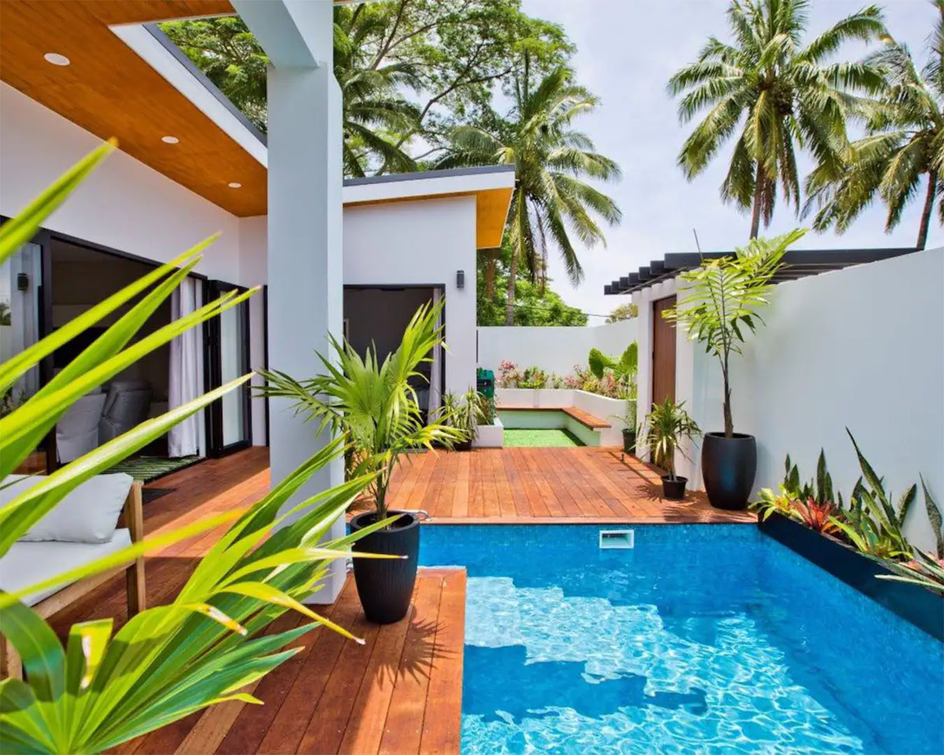 A stunning airbnb in Raro shows a pool and expansive living area with a wooden deck.