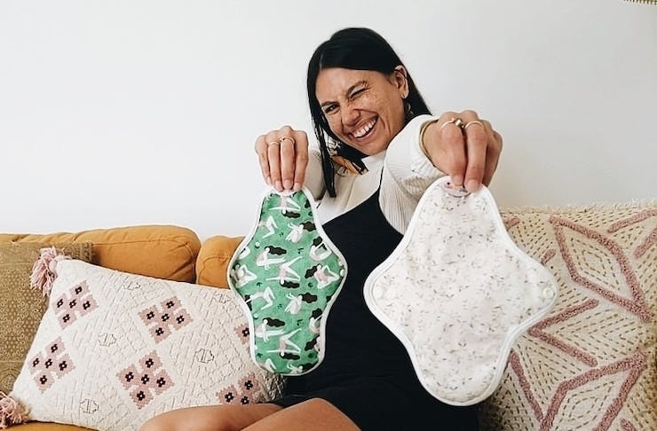 A woman holds two cloth pads with vibrant patterns.