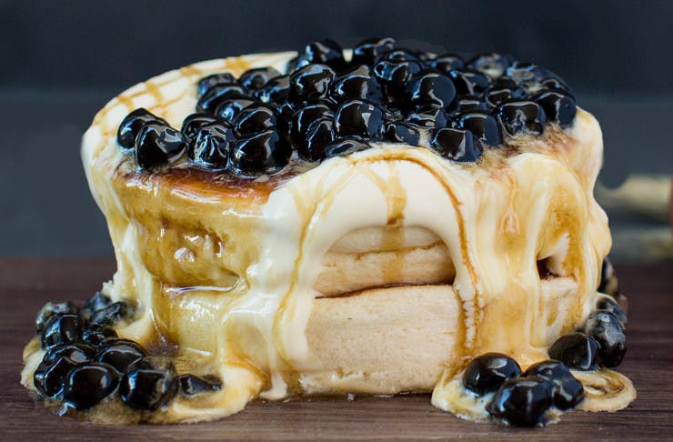 Two souffle pancakes topped with cream, syrup and berries
