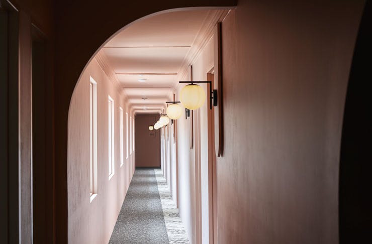 An arched hallway painted soft pink at Kyah Boutique Hotel