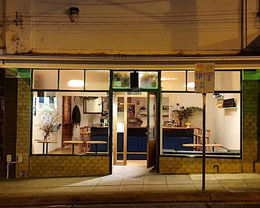 A charming restaurant lit up at night on a sloped street.