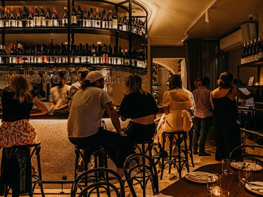 People sitting at the curved lamplit bar at La Salut in Redfern. 