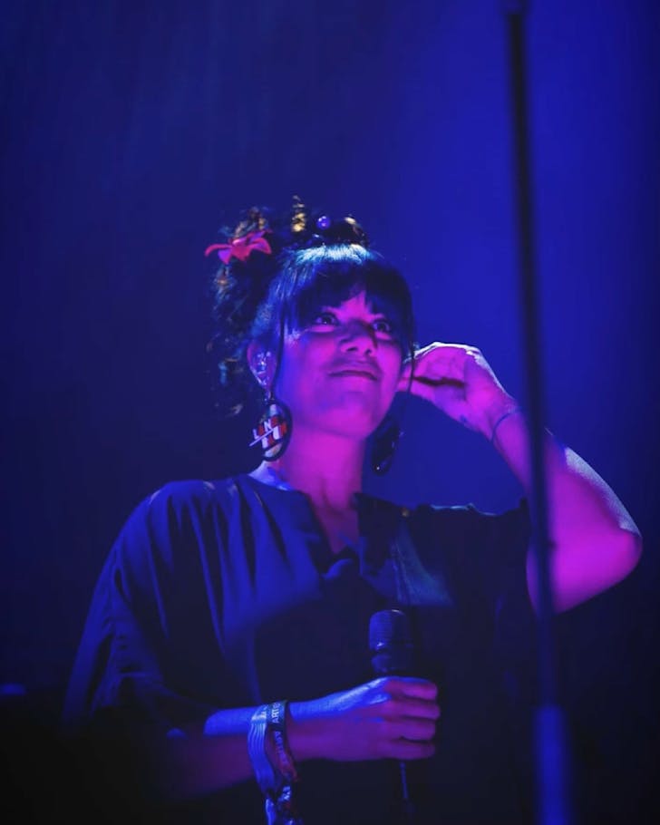Ladi6 stands on a blue and pink lighted stage.