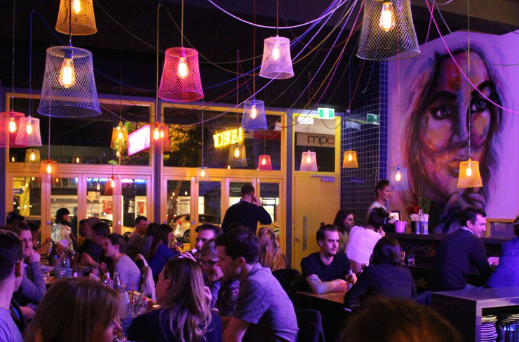 People eating inside one of the best restaurants in Richmond with hanging lights and painted murals on the wall.