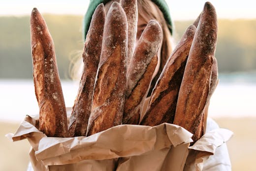 A person holding a bag of baguettes from Lagom Bakery