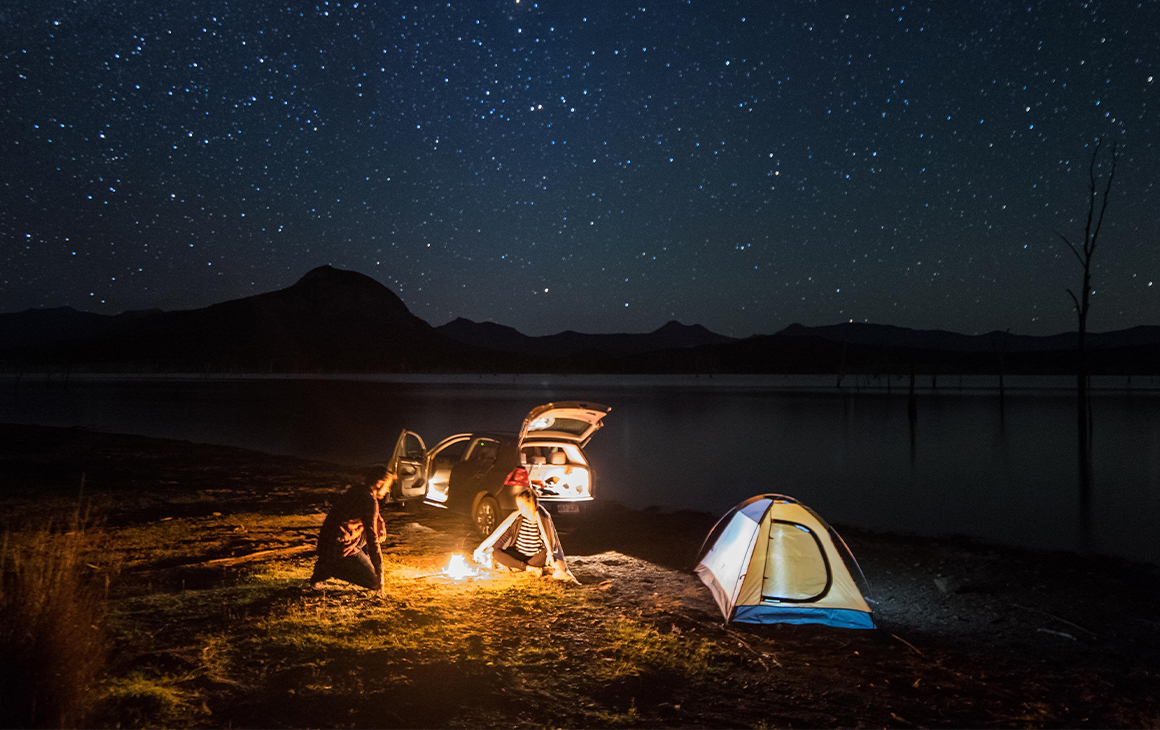 a tent and campfire by a lake at night