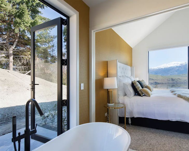 A stunning private bathroom looks out onto woodland with the lake and bedroom beyond.
