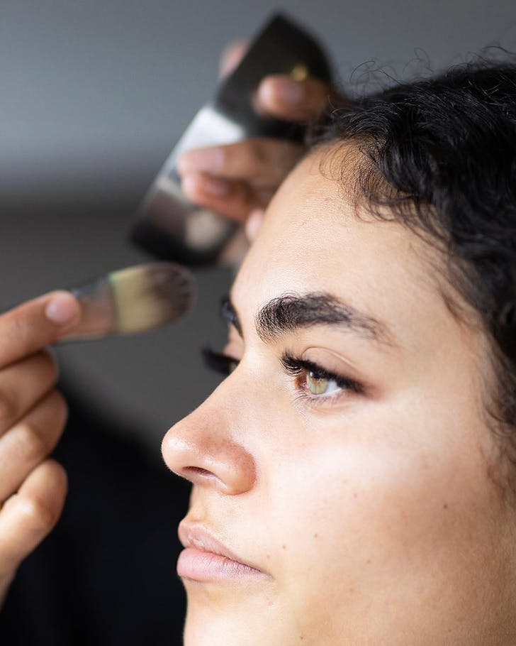 A model with fierce brows has makeup applied.