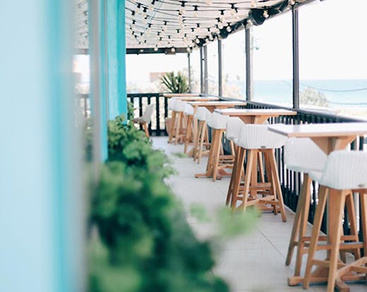 The pastel interior of Las Palmas in Palm Beach with a blurry ocean view in the background.