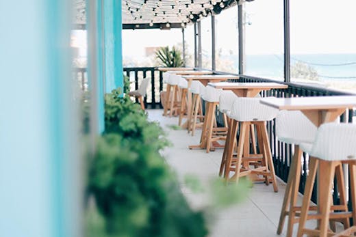 The pastel interior of Las Palmas in Palm Beach with a blurry ocean view in the background.