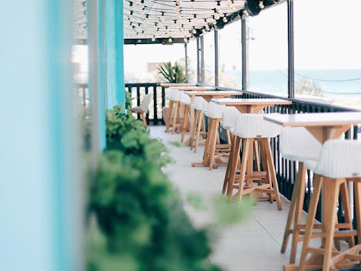 The pastel interior of Las Palmas in Palm Beach with a blurry ocean view in the background.