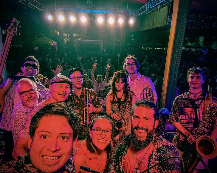 Grupo Sa-Son pose for a group selfie on stage before a crowd.