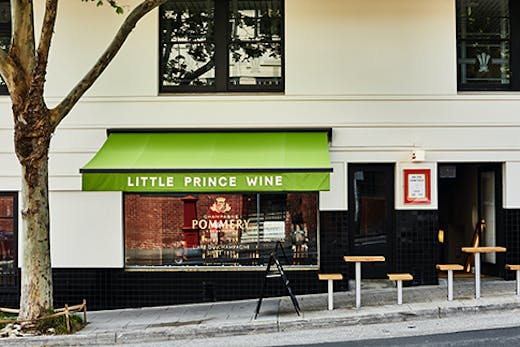 A small wine bar on a sloped street. Text on the awning reads