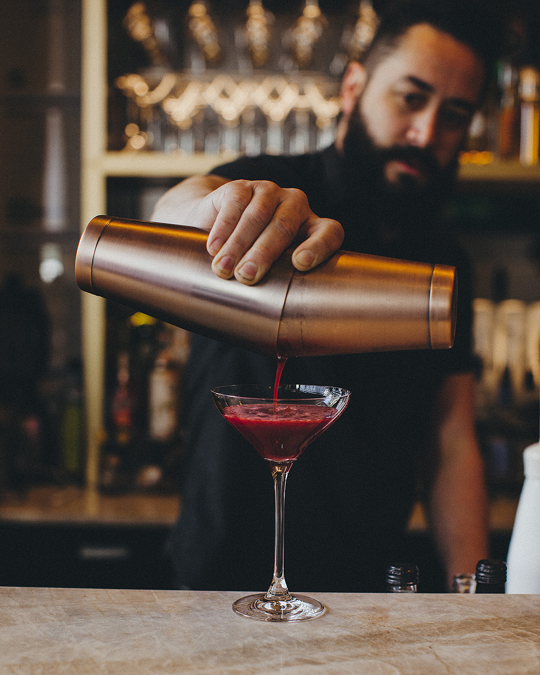 A bartender prepares a drink with panache at Little Culprit.