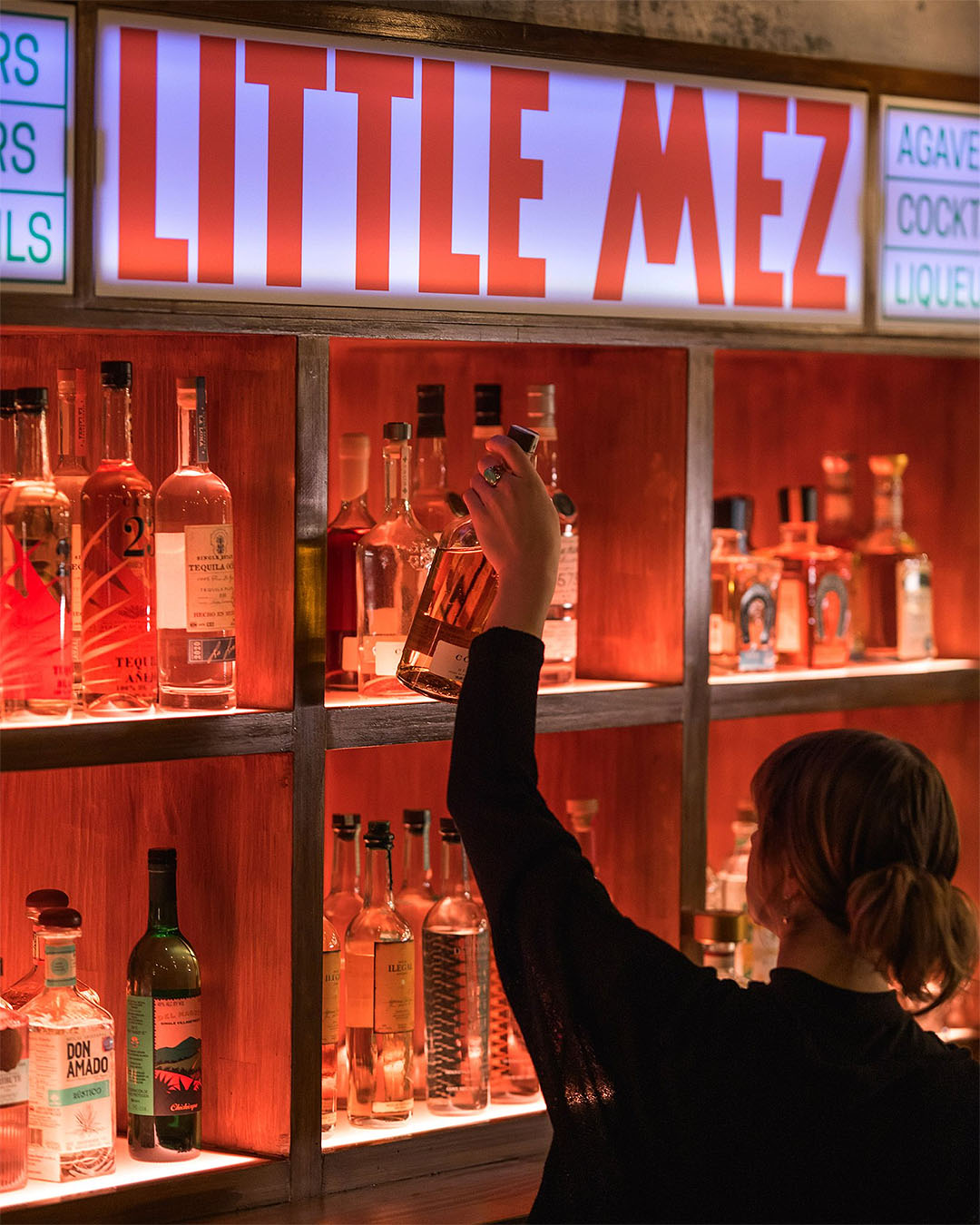 Someone reaches for a bottle at Little Mez, Queenstown's coolest new bar.