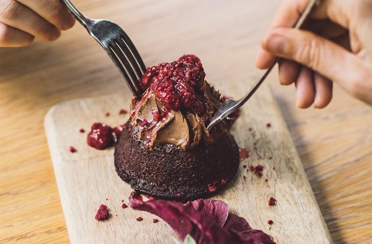 Two hands dig into a beautiful chocolate dessert from Little Bird.