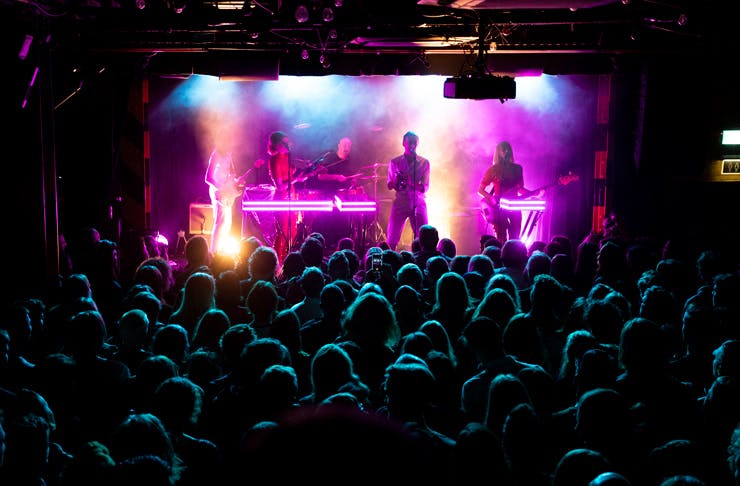 A crowd at Oxford Art Factory watching a band on stage under bright neon lights. 