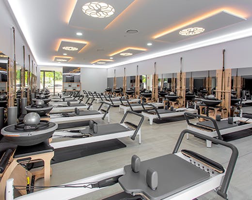 The bright interior of the Live Pilates studio with various empty Pilates machine arranged in rows.